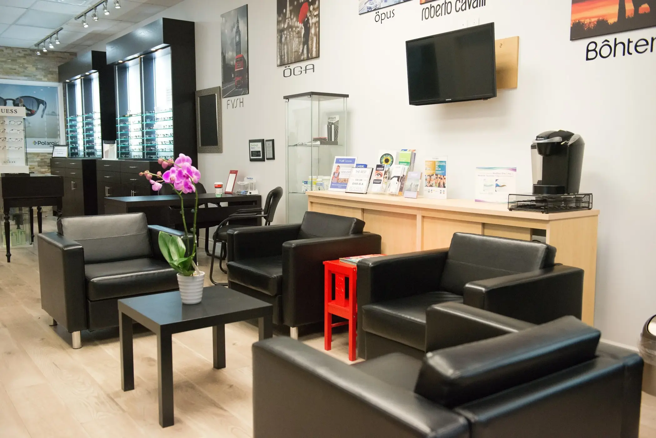 The RevitalEyes waiting area with couches, eyewear displays and a wall-mounted TV